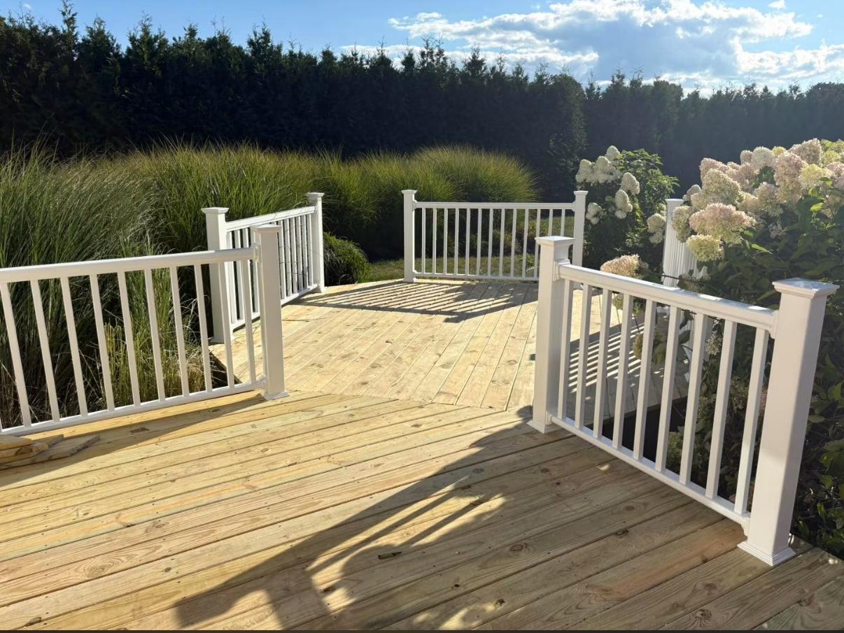 Deck with new white railings surrounded by ornamental grasses and hydrangeas